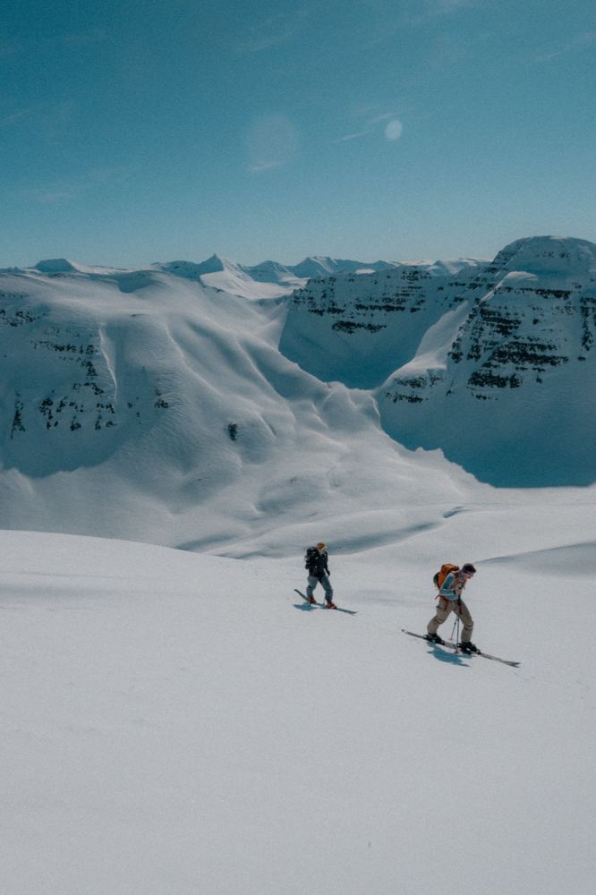 Due sciatori in discesa su pendio innevato sopra il fiordo, Islanda